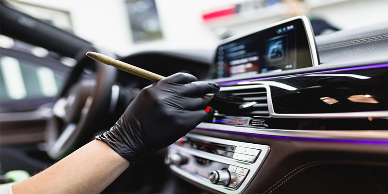 Professional interior detailing service in a car, focusing on cleaning and restoring dashboard and controls by Broward Detailers in South Florida.