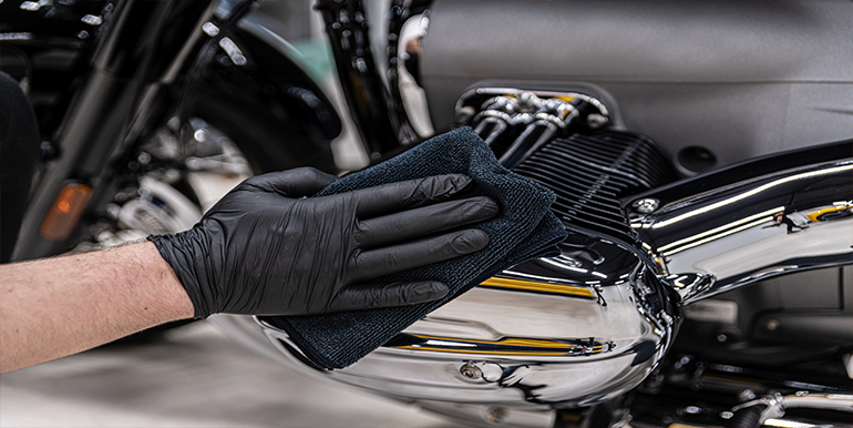 Expert motorcycle detailing service in South Florida, showcasing a technician polishing chrome parts for a spotless shine.