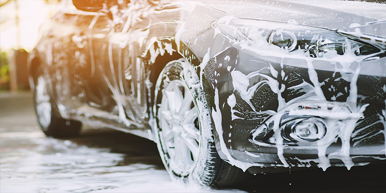 Professional neutral pH carwash service in South Florida, showcasing a car covered in foam during a thorough wash for paint protection.