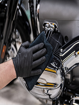 Professional motorcycle detailing in South Florida, featuring a technician cleaning chrome components with a microfiber cloth for a brilliant finish.