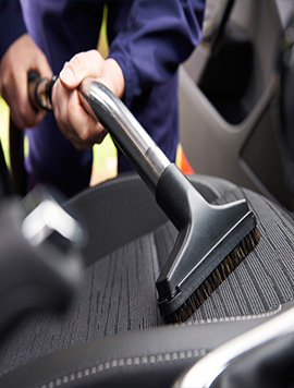 Professional pet hair removal service in South Florida, showcasing a technician vacuuming pet hair from vehicle upholstery for a clean and allergen-free interior.