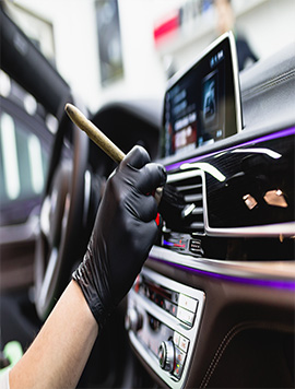 Expert interior detailing service by Broward Detailers, showcasing meticulous cleaning of car dashboard and controls with professional techniques in South Florida.