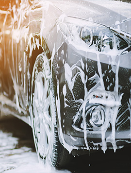 Close-up of a car being washed with neutral pH foam, highlighting the cleaning process and paint protection in South Florida.